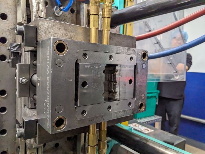 Moule d’injection plastique monté sur presse, avec ses raccords de refroidissement, dans un atelier de plasturgie.