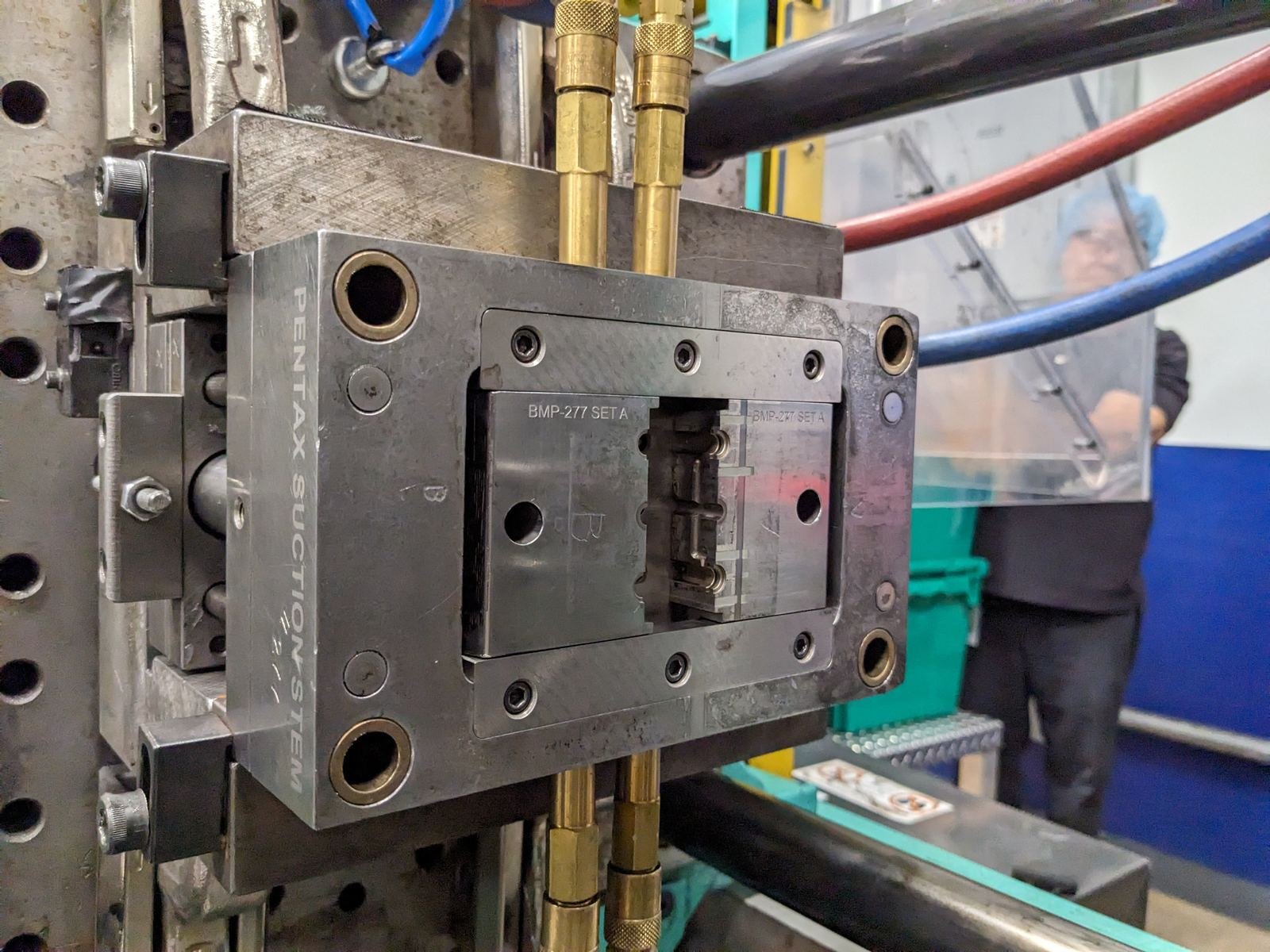 Moule d’injection plastique monté sur presse, avec ses raccords de refroidissement, dans un atelier de plasturgie.
