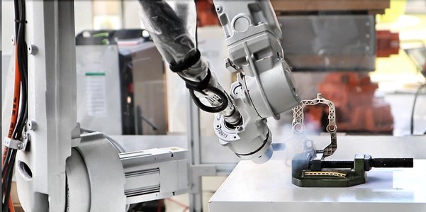 Cellule robotisée réalisant un ébavurage automatisé par projection de glace carbonique sur une pièce industrielle.