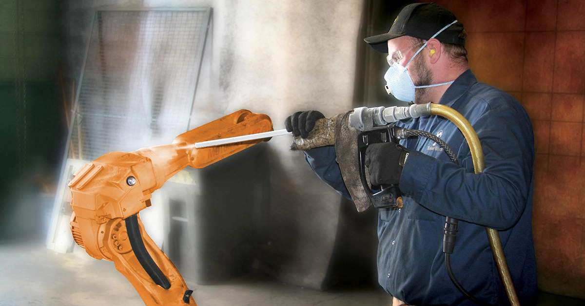 Un homme nettoie le bras d'un robot avec de la glace carbonique.